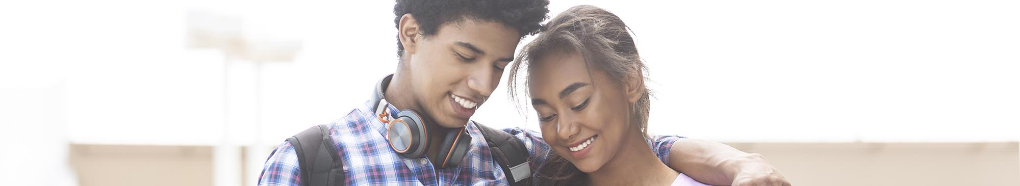 Two smiling teenagers looking down at cell phone
